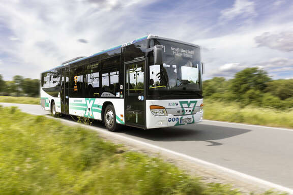 Bus der Linie X71 Bus mit Aufschrift X auf Straße in grüner Landschaft