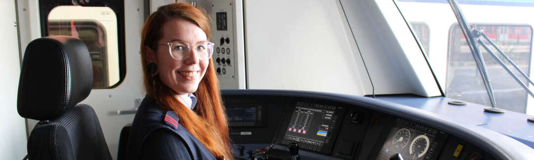 Lokführerin Larena Dana Zinkel Frau in der Führerkabine einer S-Bahn mit Monitoren und Fahrplanheft