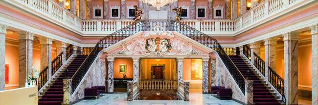 Der Marmorsaal mit Kronleuchter, doppeltem Treppenaufgang und Empore mit Säulengängen.