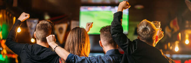 Public viewing Jubelnde Fans in einem Lokal vor einem Monitor