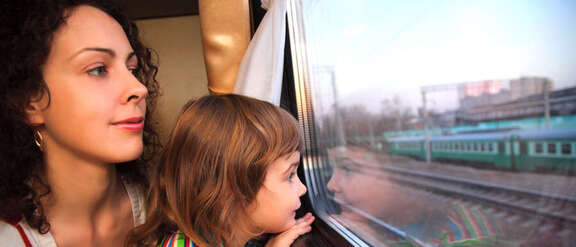 Frau und Kind auf dem Schoß schauen aus dem Zugfenster